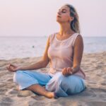 woman in meditation pose on a beach